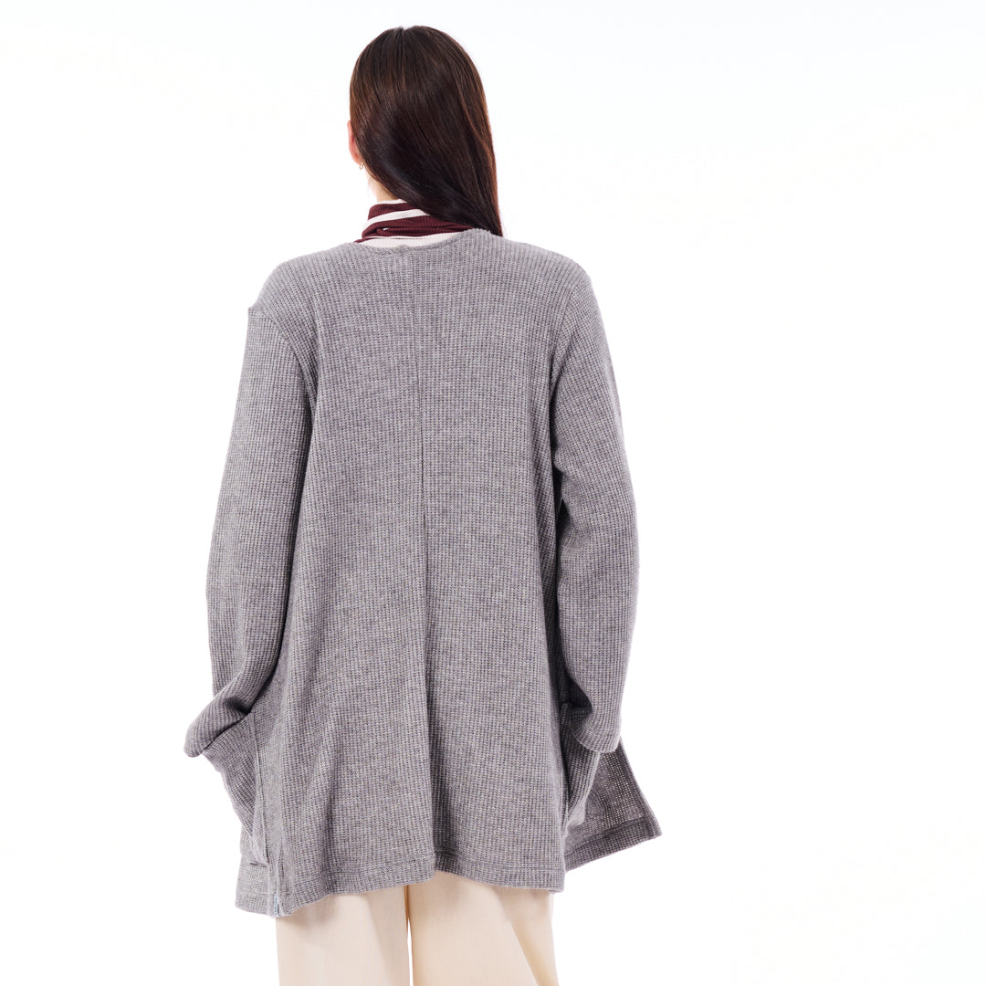 Person wearing a gray cardigan on a white background