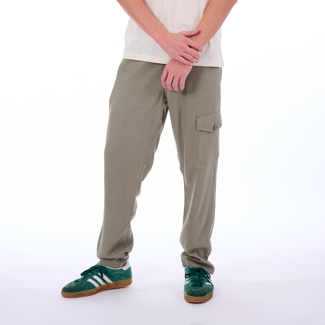 Person wearing beige cargo pants and green sneakers on a white background