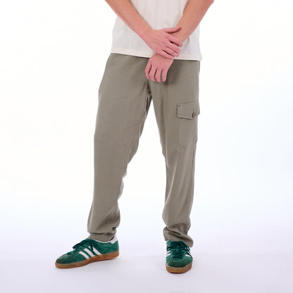 Person wearing beige cargo pants and green sneakers on a white background