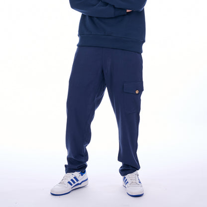 Person wearing a navy tracksuit with white sneakers on a white background