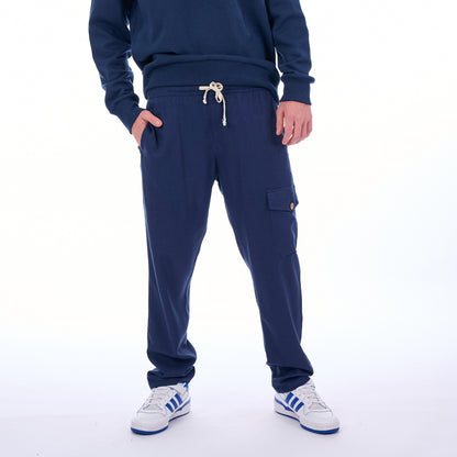 Person wearing a navy tracksuit with white Adidas shoes on a white background