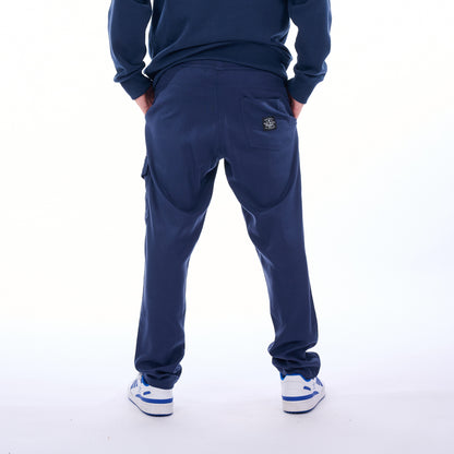 Person wearing navy blue tracksuit with white sneakers on a white background