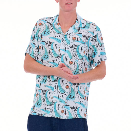 Person wearing a patterned shirt with dolphins and palm trees on a white background