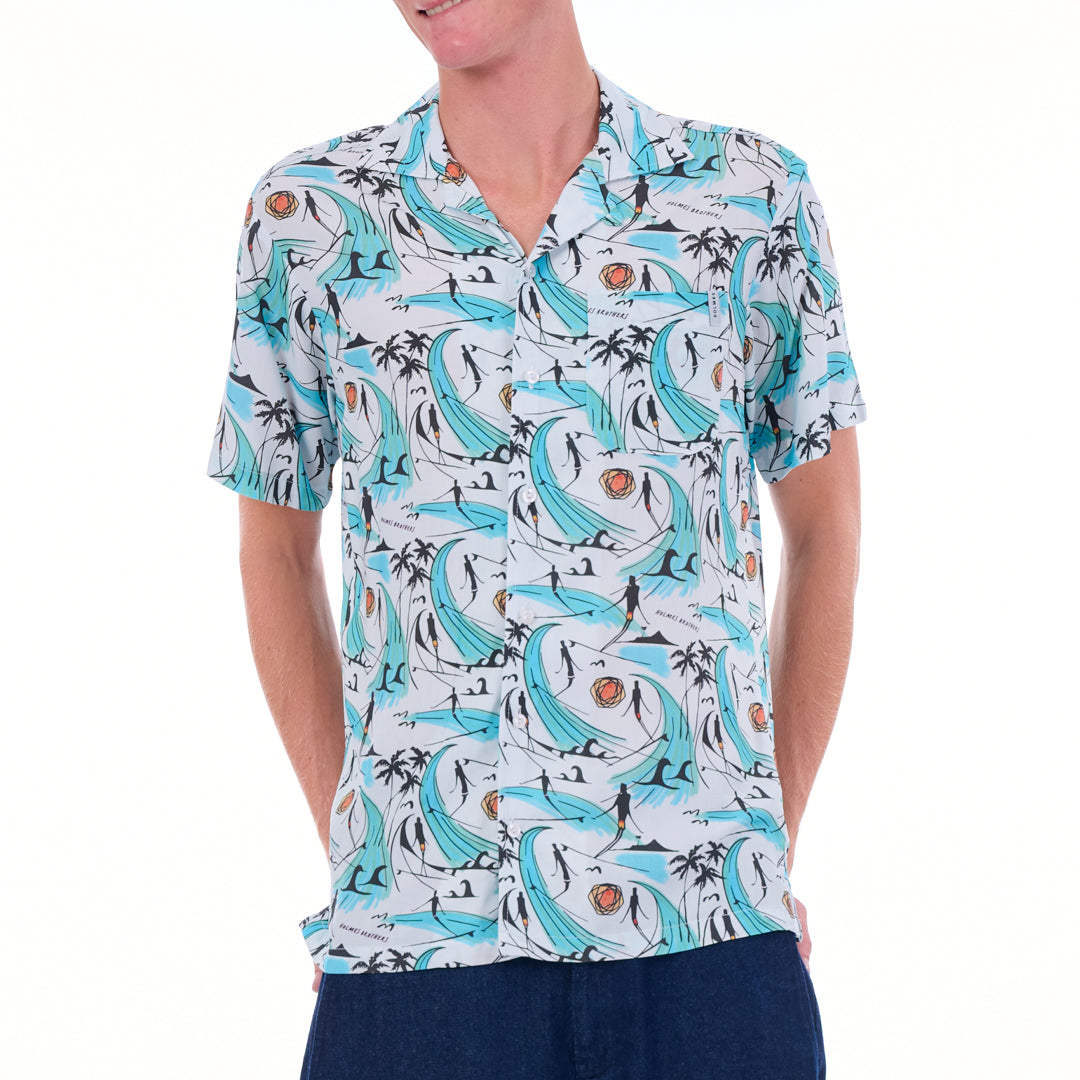 Person wearing a patterned shirt with dolphins and palm trees on a white background