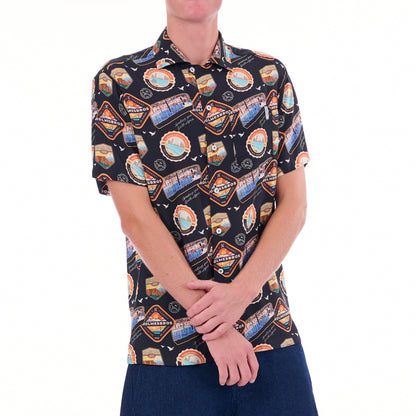 Person wearing a patterned shirt with various logos on a white background