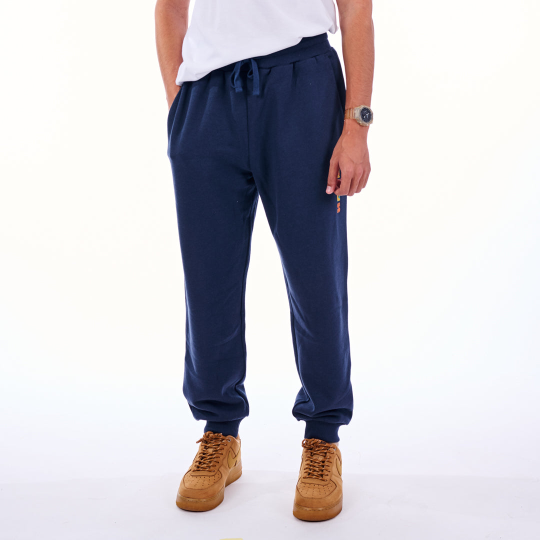 Person wearing navy blue jogger pants and tan shoes on a white background