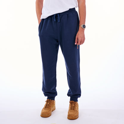 Person wearing navy blue jogger pants and tan shoes on a white background