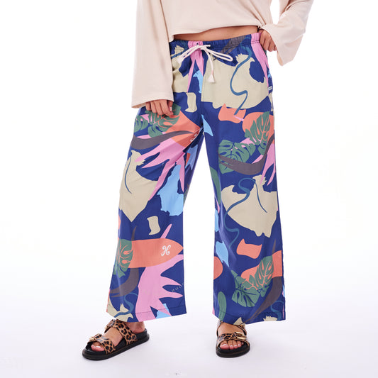 Colorful tropical leaf-patterned pants worn by a person on a white background
