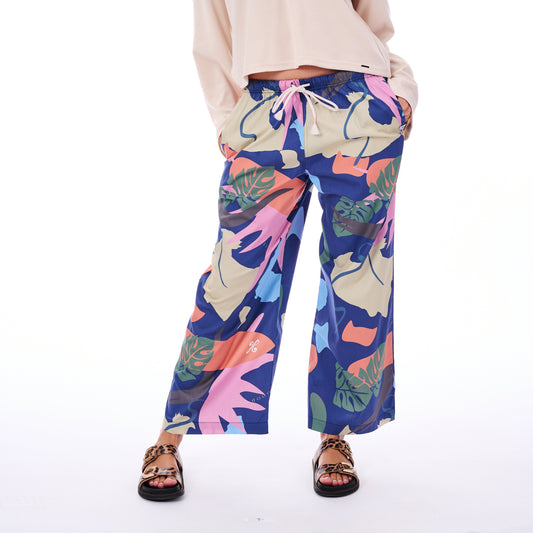 Person wearing colorful tropical leaf patterned pants on a white background