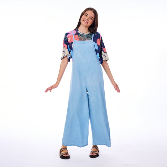 Woman wearing a blue jumpsuit with a colorful top on a white background