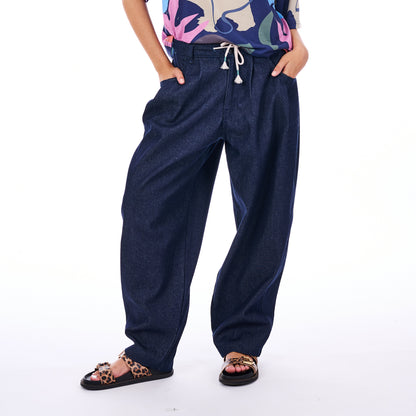 Person wearing blue denim pants with a colorful top on a white background