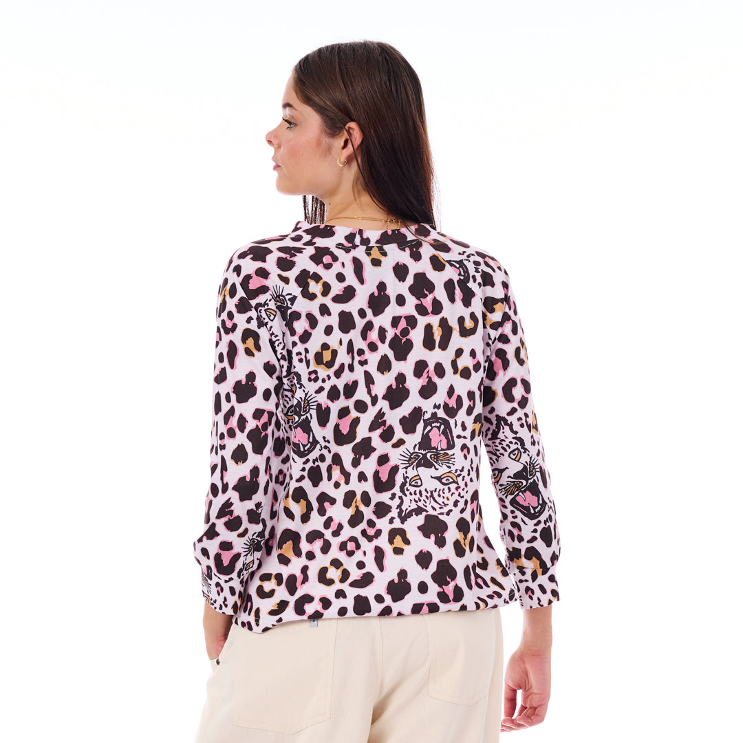 Woman wearing a leopard print top with colorful designs on a white background