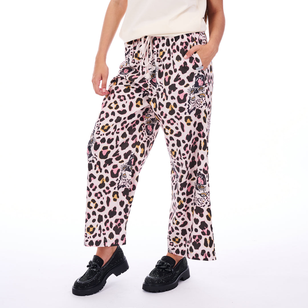 Person wearing leopard print pants with pink accents on a white background