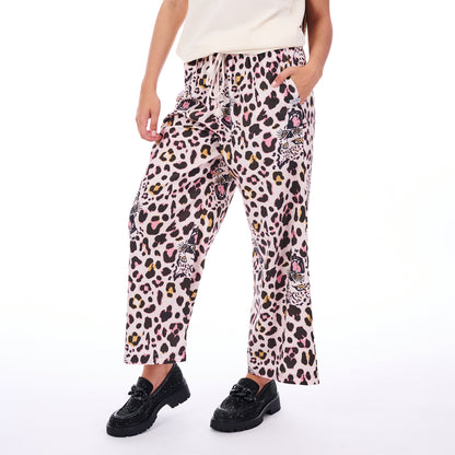 Person wearing leopard print pants with pink accents on a white background
